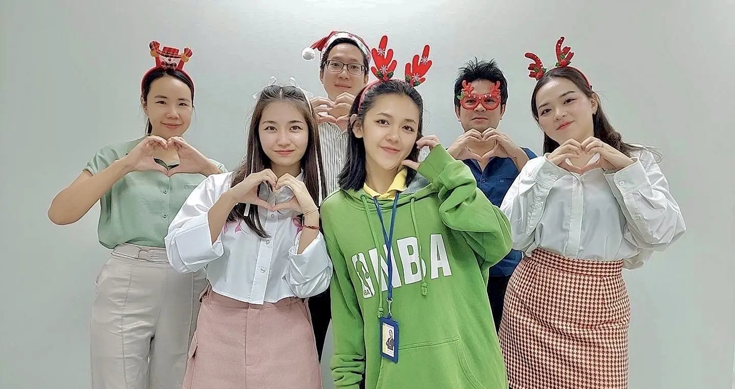 法律事務所のスタッフと笑顔で写真を撮るタイ人弁護士クワン